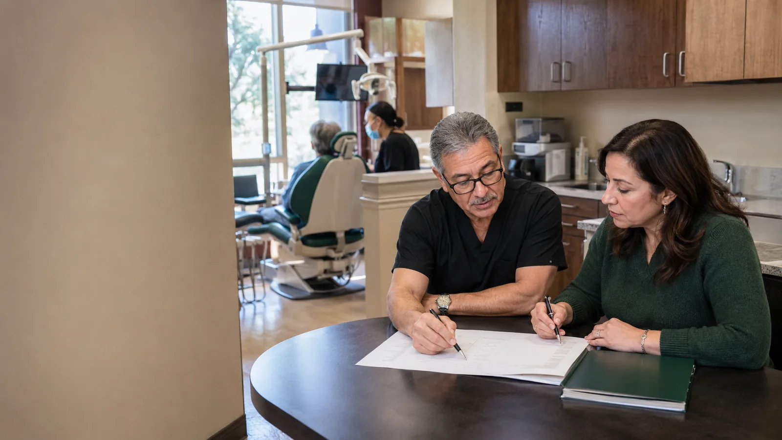 A dentist and an advisor reviewing a practice plan together at a table.